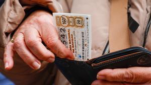 Una mujer mete un décimo de lotería en su monedero.