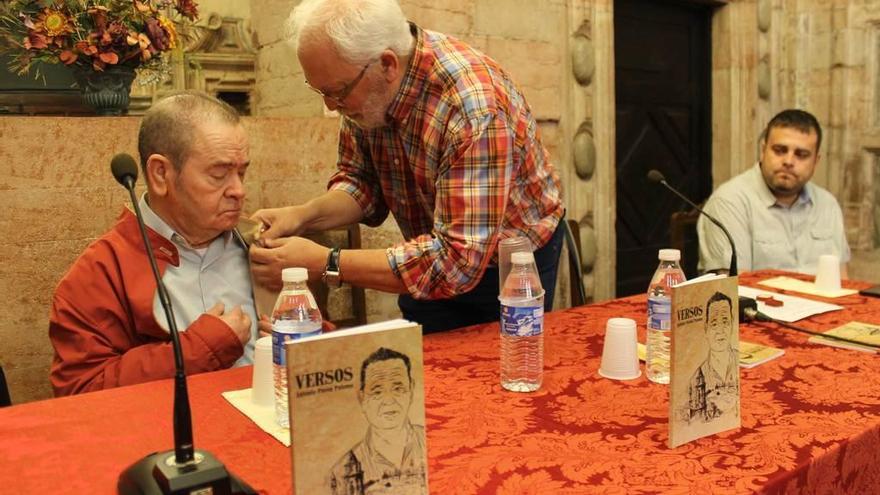 El presidente de la asociación cultural &quot;Valentín Andrés&quot; coloca la insignia de oro a Antonio Pavón ante la mirada del cronista oficial del concejo, Gustavo Adolfo Fernández.