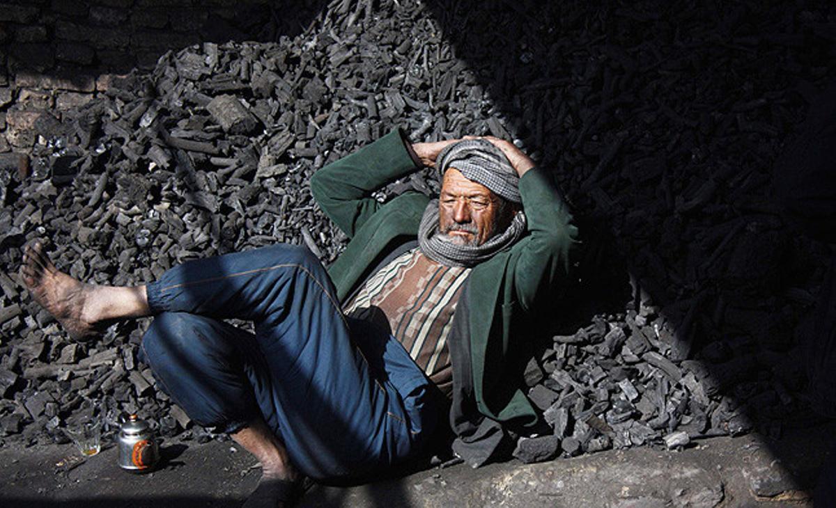 Un afganès descansa sobre el carbó que ven de abans que arribi el fred, a Kabul, Afganistan.