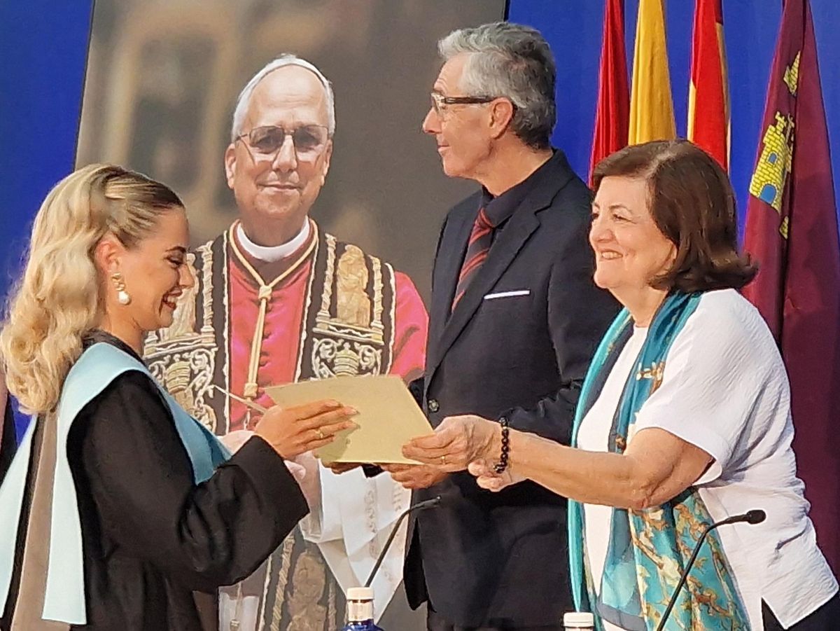 La presidenta de la UCAM entrega el diploma a una estudiante.