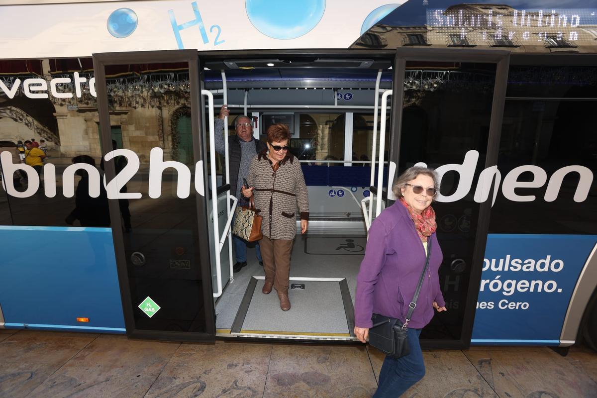 Tres personas inspeccionan el prototipo de autobús impulsado por hidrógeno verde