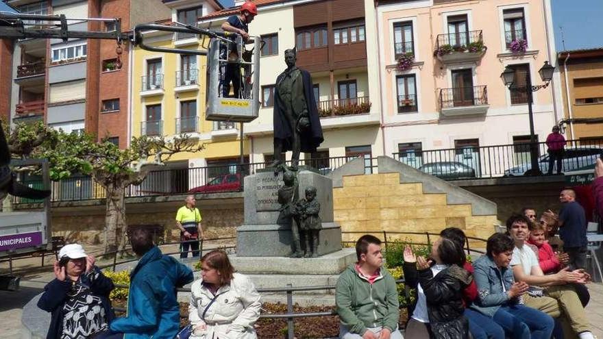 Uno de los miembros de Adepas coloca la montera y la capa a la escultura de Pedro Alonso.