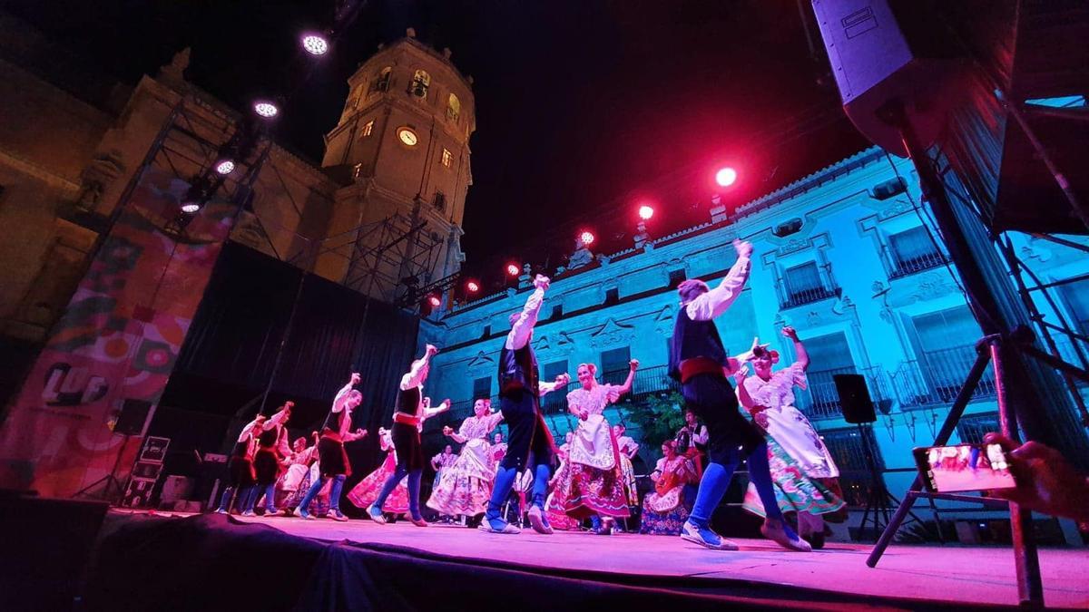 Coros y Danzas Virgen de las Huertas durante una actuación en la Plaza de España con la antigua colegial de San Patricio al fondo.