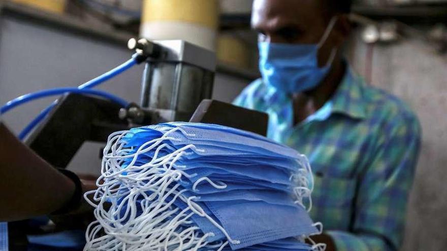 Un trabajador de la India fabrica mascarillas.