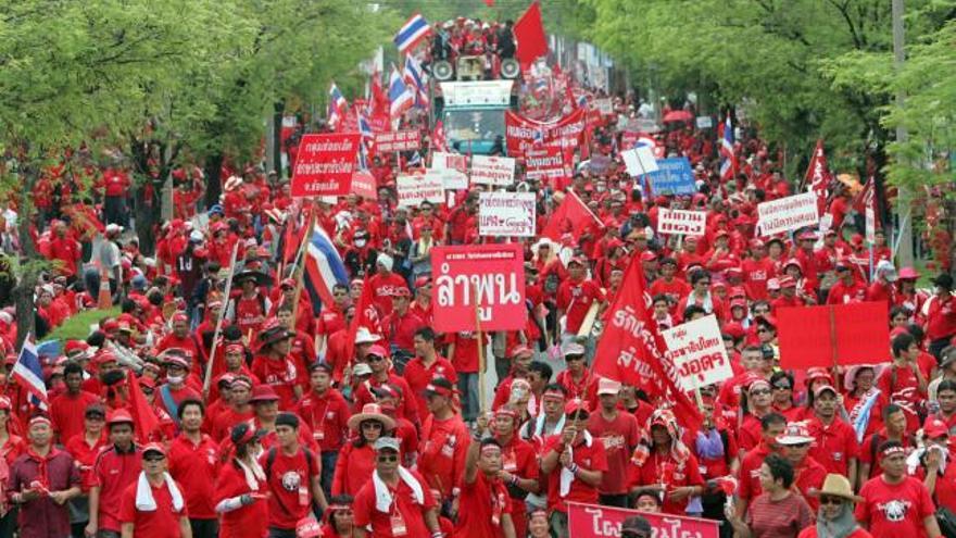 Simpatizantes del ex primer ministro tailandés Thaksin Shinawatra vestidos de rojo marchan en dirección a la residencia del presidente del consejo real, Prem Tisunalonda, en Bangkok (Tailandia).