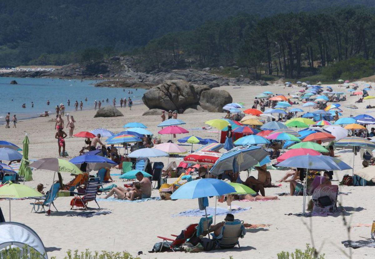 Unos adolescentes se refrescan con agua en el paseo de Rodeira, con la playa al fondo. | Santos Álvarez