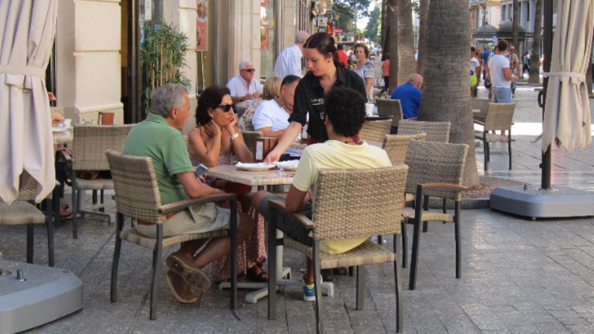 Una camarera atiende a la clientela en la terraza de un bar.