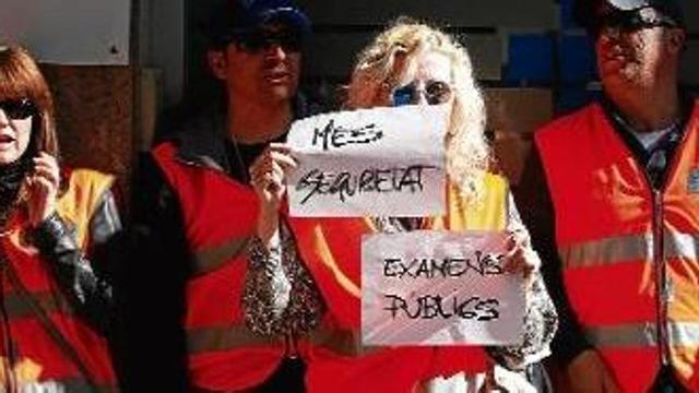 Una de les examinadores mostrant una pancarta a favor de més seguretat i que els exàmens siguin públics.