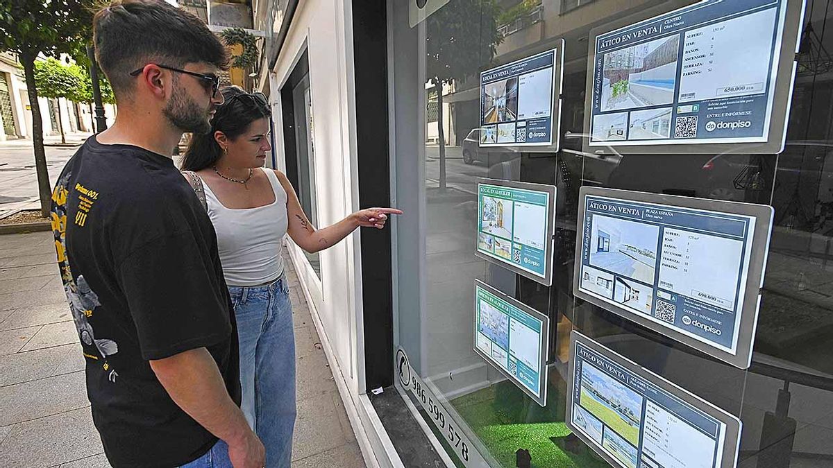 Personas viendo el escaparate de una inmobiliaria en Vigo.