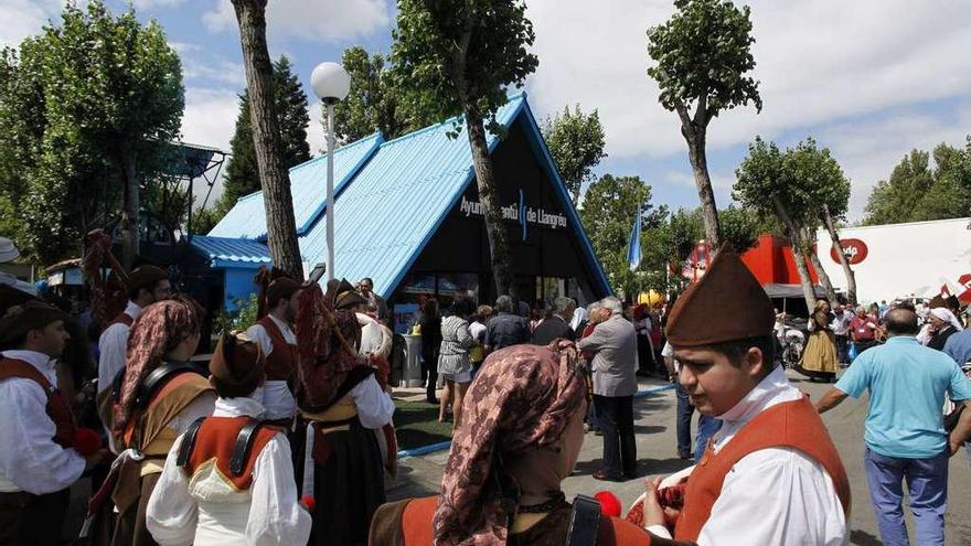 Los componentes de la Banda de Gaitas &quot;Conceyu Llangréu&quot;, en el pabellón de Langreo, junto a los visitantes a la Feria.