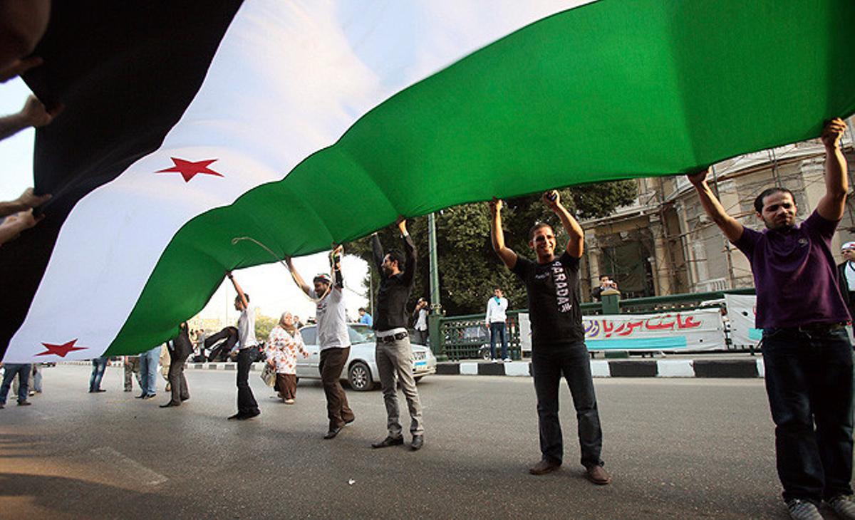 Diversos sirians subjecten una gran bandera siriana durant una protesta contra la reunió que els ministres àrabs d’Exteriors preveuen celebrar a la seu de la Lliga Àrab al Caire, Egipte.