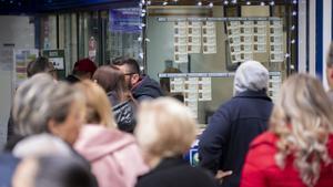 Ciudadanos buscan su número de lotería en una administración.