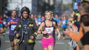 Un bombero y una ’runner’, durante  la cursa dels Bombers de Barcelona celebrada en octubre del 2016.