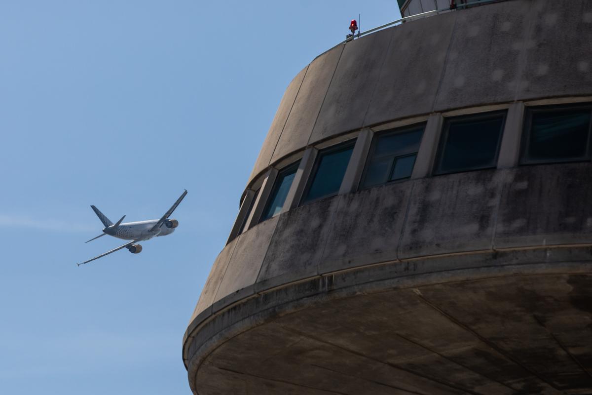 Un avión de Vueling pasa cerca de la torre de control del aeropuerto de Barcelona.