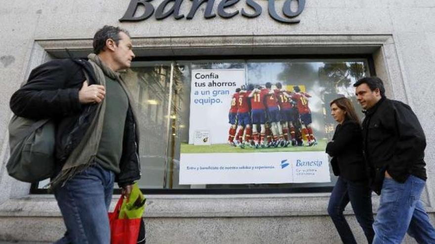 Varios viandantes pasan frente a una sucursal de Banesto en Madrid.  // Andrea Comas/Reuters