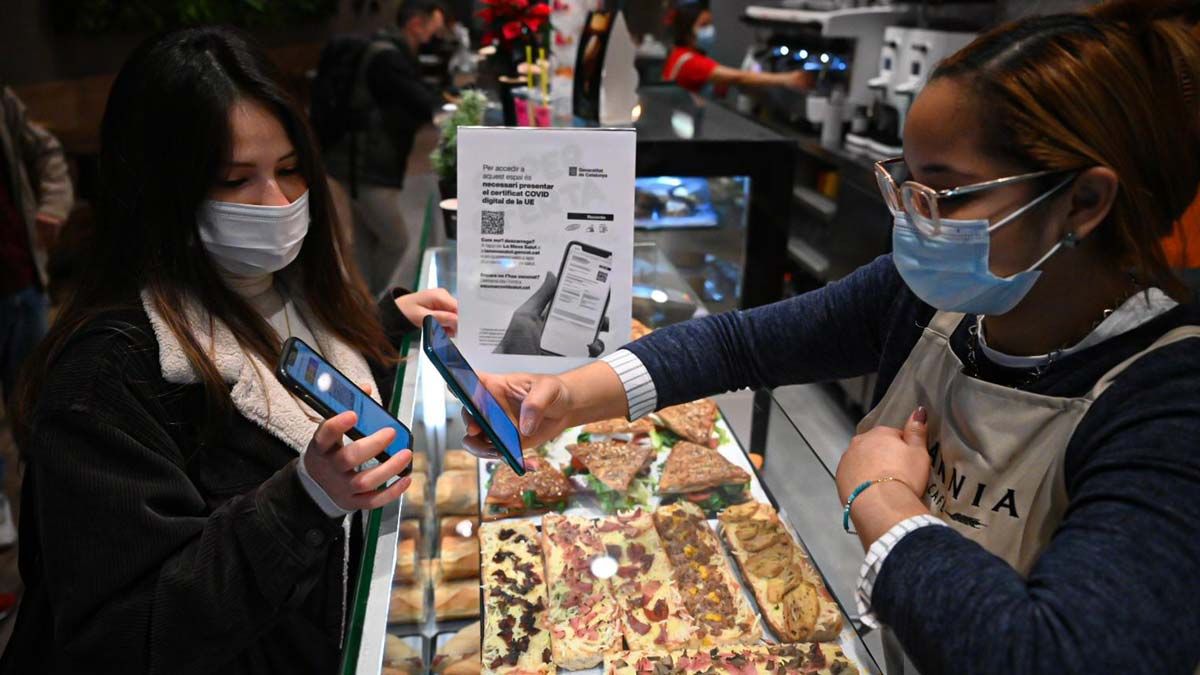 Una empleada de un bar del Eixample, en Barcelona, escanea el pasaporte covid de una clienta, en el primer día de entrada en vigor de la medida