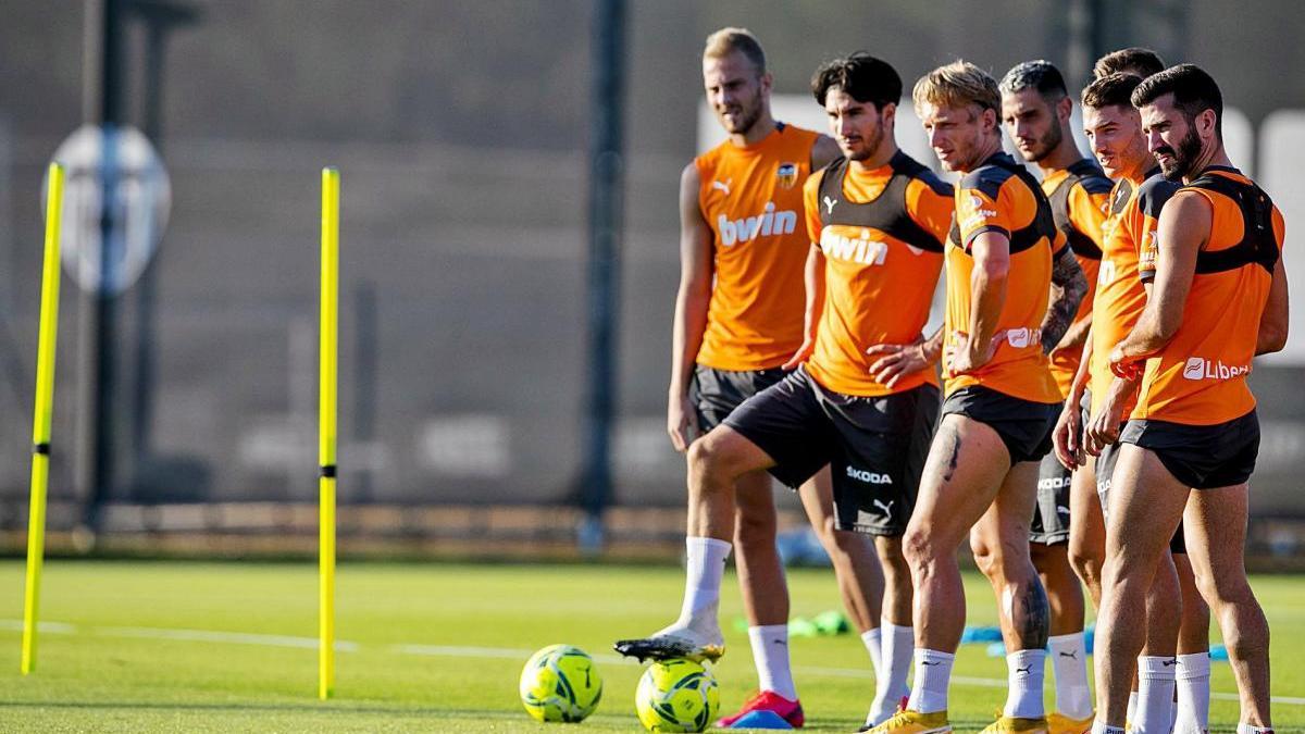 Varios futbolistas del Valencia CF, concentrados durante el entrenamiento ayer en Paterna.