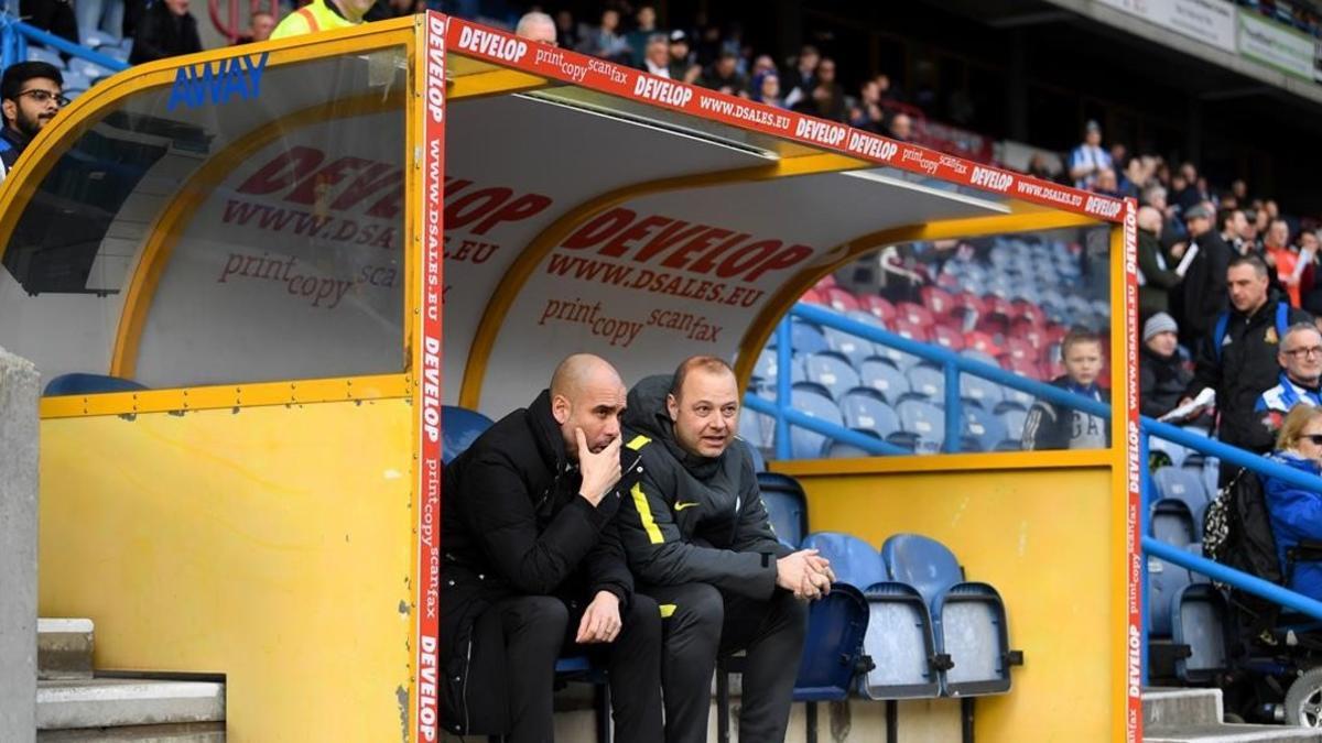 Guardiola charla con Rodolf Borrell, asistente suyo, en el banquillo del estadio del Huddersfield.