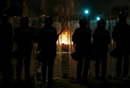 Riot police stand guard in front of a fire set by protesters at a junction in Mongkok district