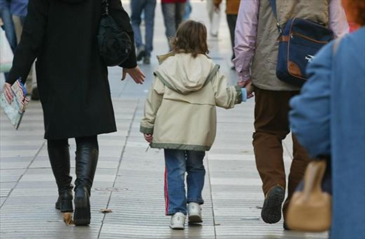 Unos padres pasean con su hijo, cogidos de la mano.