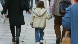 Unos padres pasean con su hijo, cogidos de la mano.