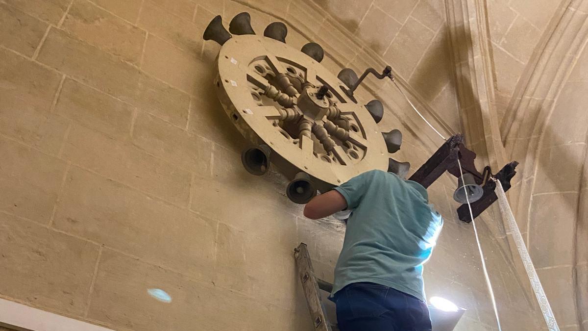 El restaurador del museo descuelga las tres campanas de la rueda para su limpieza