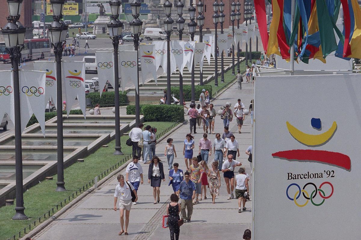 Numerosas y coloridas banderolas con el logo de los Juegos Olímpicos en la avenida de la Reina María Cristina, a la altura del centro de prensa de los Juegos, el 25 de julio del 2023