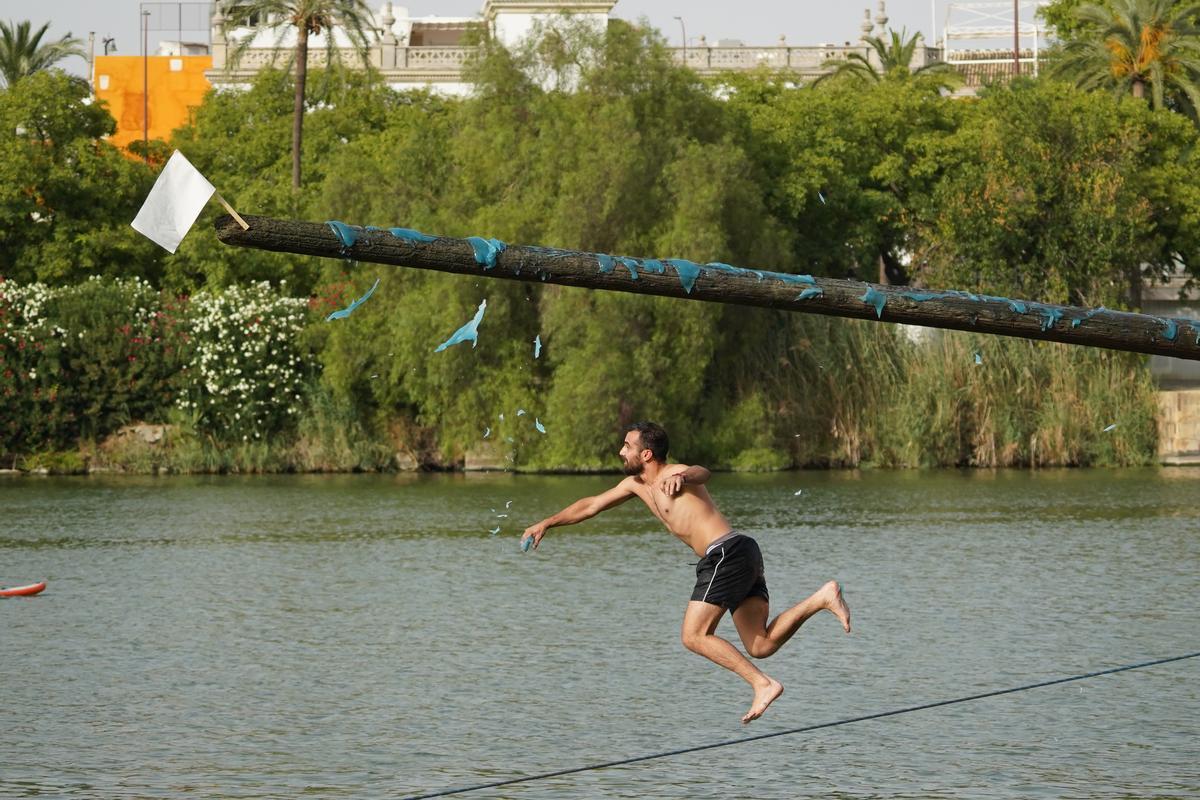 La 'cucaña', el juego centenario que regresa cada verano al río Guadalquivir por la Velá de Santa Ana en imágenes