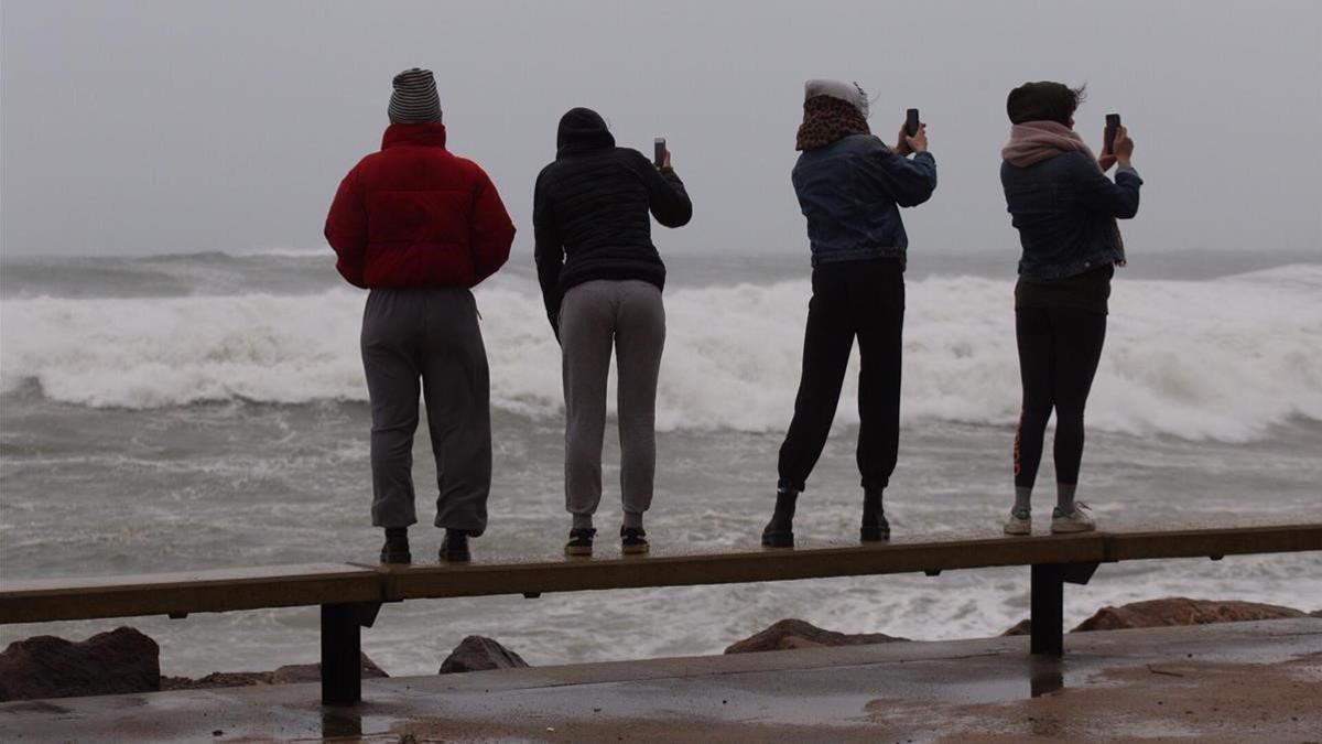 Cuatro jóvenes miran, de forma imprudente, el fuerte oleaje de la playa en Sant Antoni de Calonge.