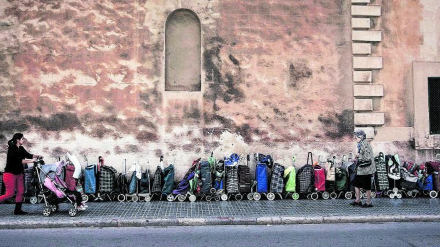 Imagen de archivo de una hilera de carritos de personas necesitadas colocados frente al Convent del Caputxins de Palma para ser llenados. | B. RAMON