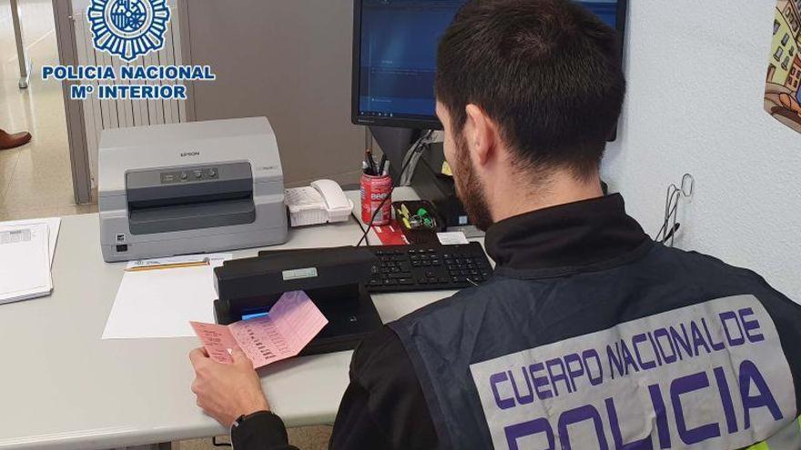 Un agente de Extranjería realiza la comprobación del carnet de conducir del detenido.