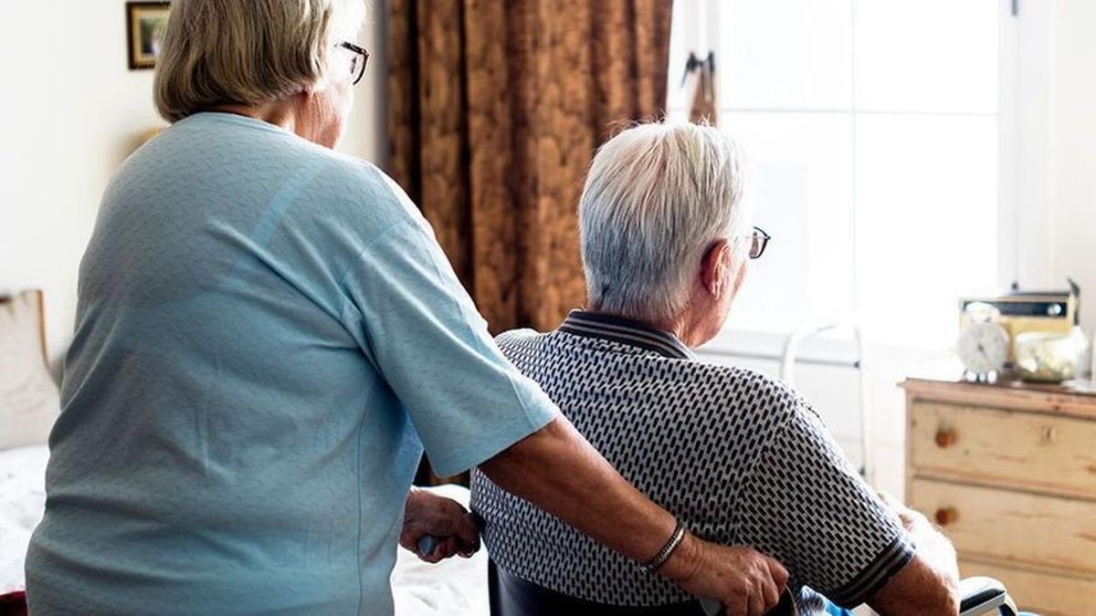 Una persona dependiente junto a una mujer que la cuida, en una imagen de archivo.