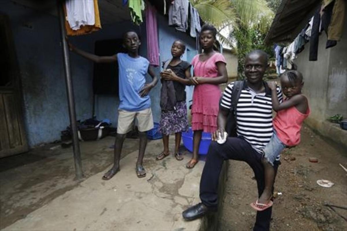 Un supervivent de l’Ebola sosté la filla d’una amiga que va morir per la malaltia, a Sierra Leone.