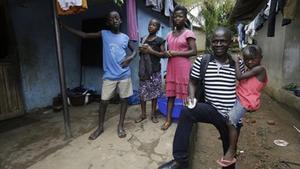 Un supervivent de l’Ebola sosté la filla d’una amiga que va morir per la malaltia, a Sierra Leone.