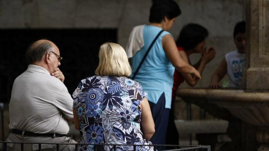 Una pareja de personas mayores charla en un banco del centro. La preocupación por el impacto de la recesión es una constante.