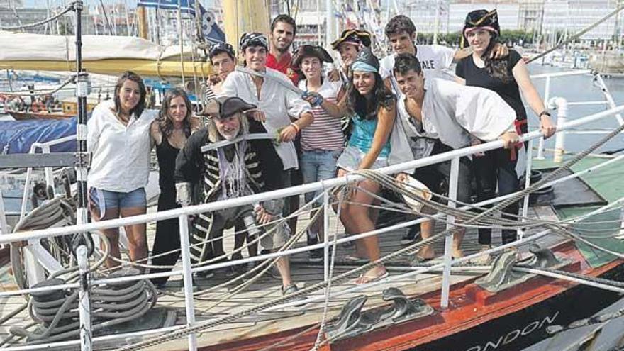 Los tripulantes coruñeses del ´Pelican of London´, ayer, a bordo del barco, disfrazados de piratas; el puesto de ´merchandising´ de la regata y el de la compañía Gadisa. / juan varela