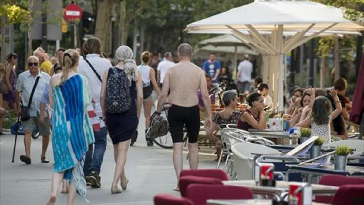 Tránsito de turistas junto a las terrazas ubicadas en la Rambla del Poblenou.