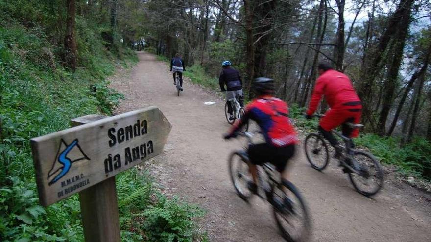 Unos ciclistas recorren la Senda da Auga por la parroquia de San Vicente de Trasmañó. // FdV