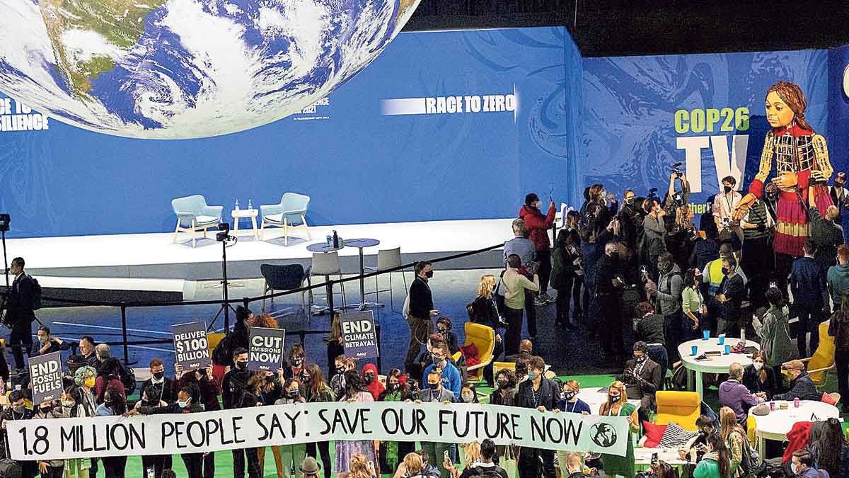 Participantes en la cumbre COP26 de Glasgow, con una pancarta reivindicativa