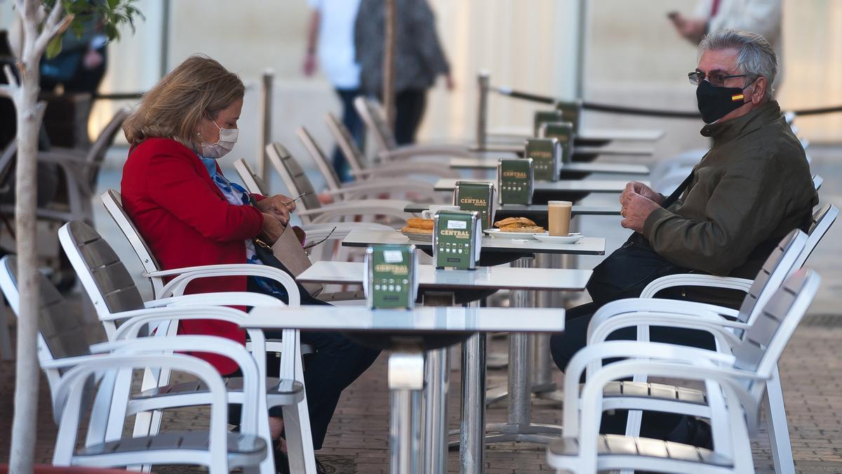 Dos personas con mascarilla en una terraza.