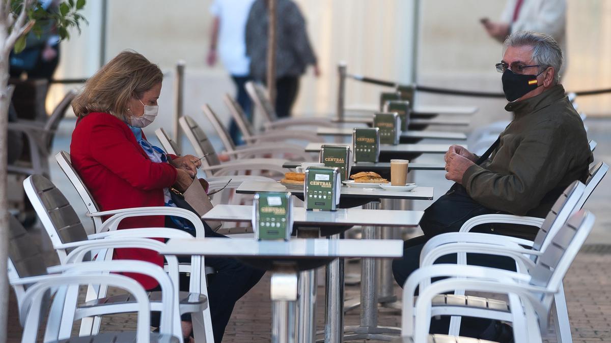 Dos personas con mascarilla en una terraza.