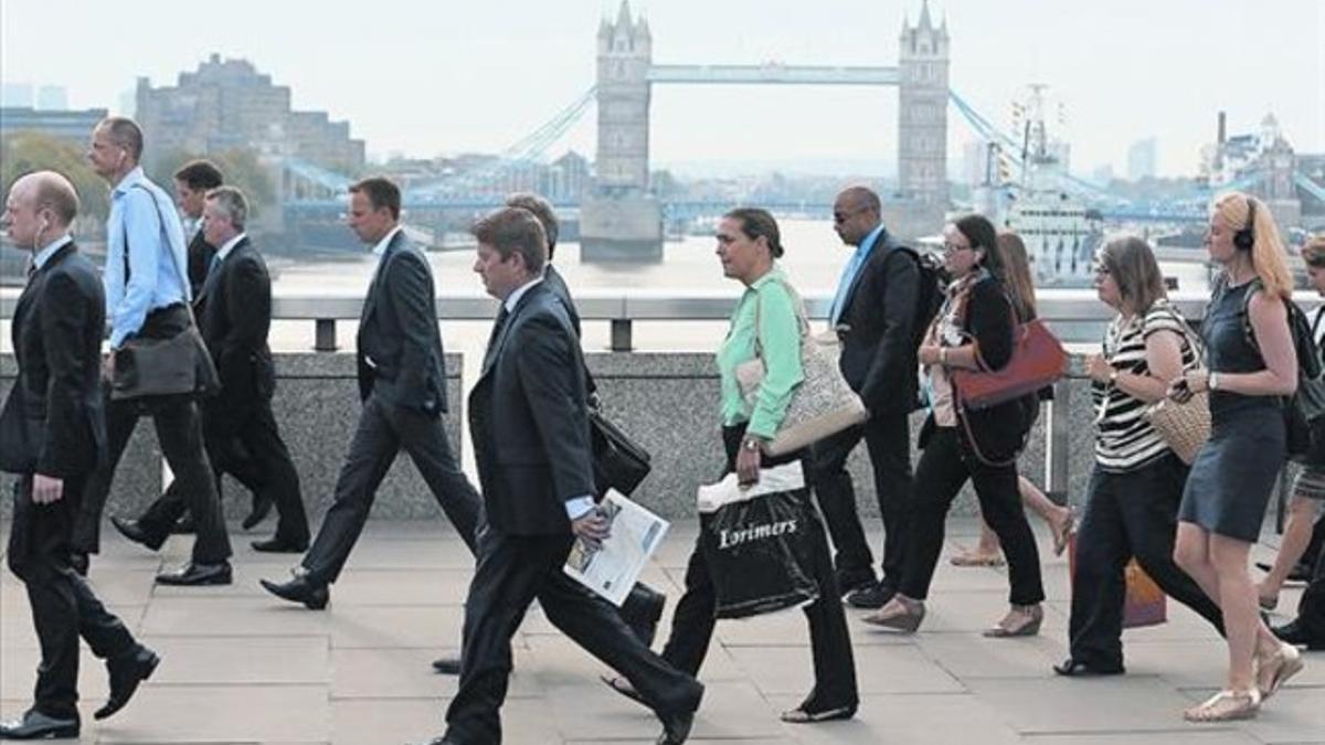 Empleados de la City londinense atraviesan el puente de Londres para dirigirse al trabajo, el pasado agosto.