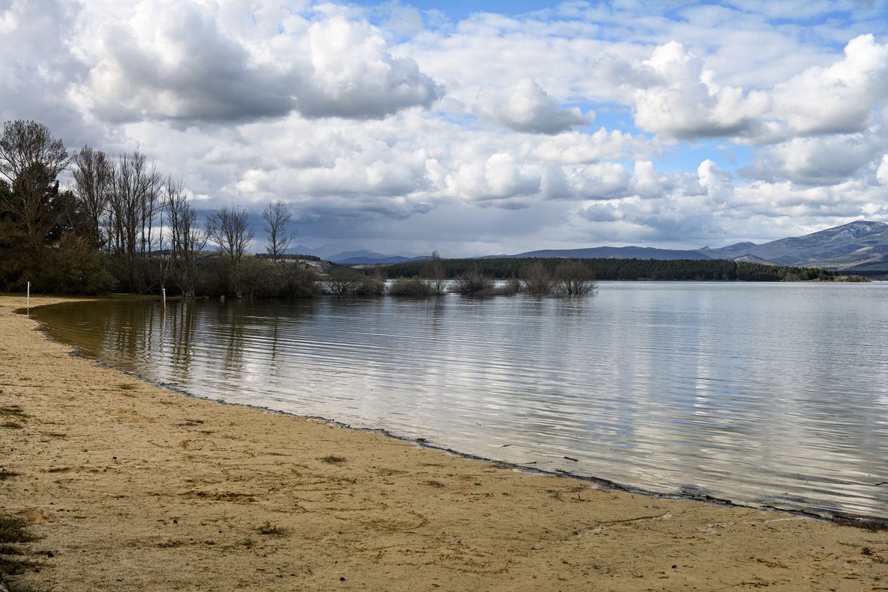 Las tranquilas aguas del embalse de Aguilar reflejan las nubes y las lejanas colinas.