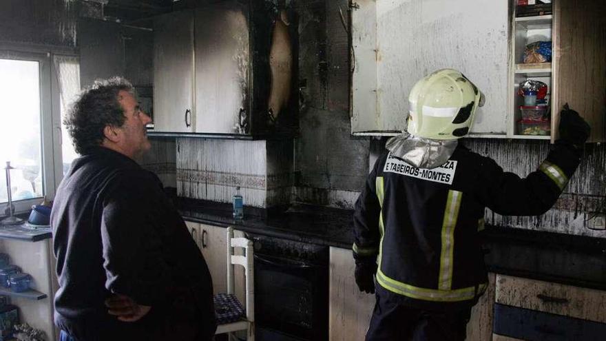 Da Costa observa, junto a un bombero, cómo quedó su cocina. A la izquierda, efectivos de emergencias. // Bernabé/Luismy