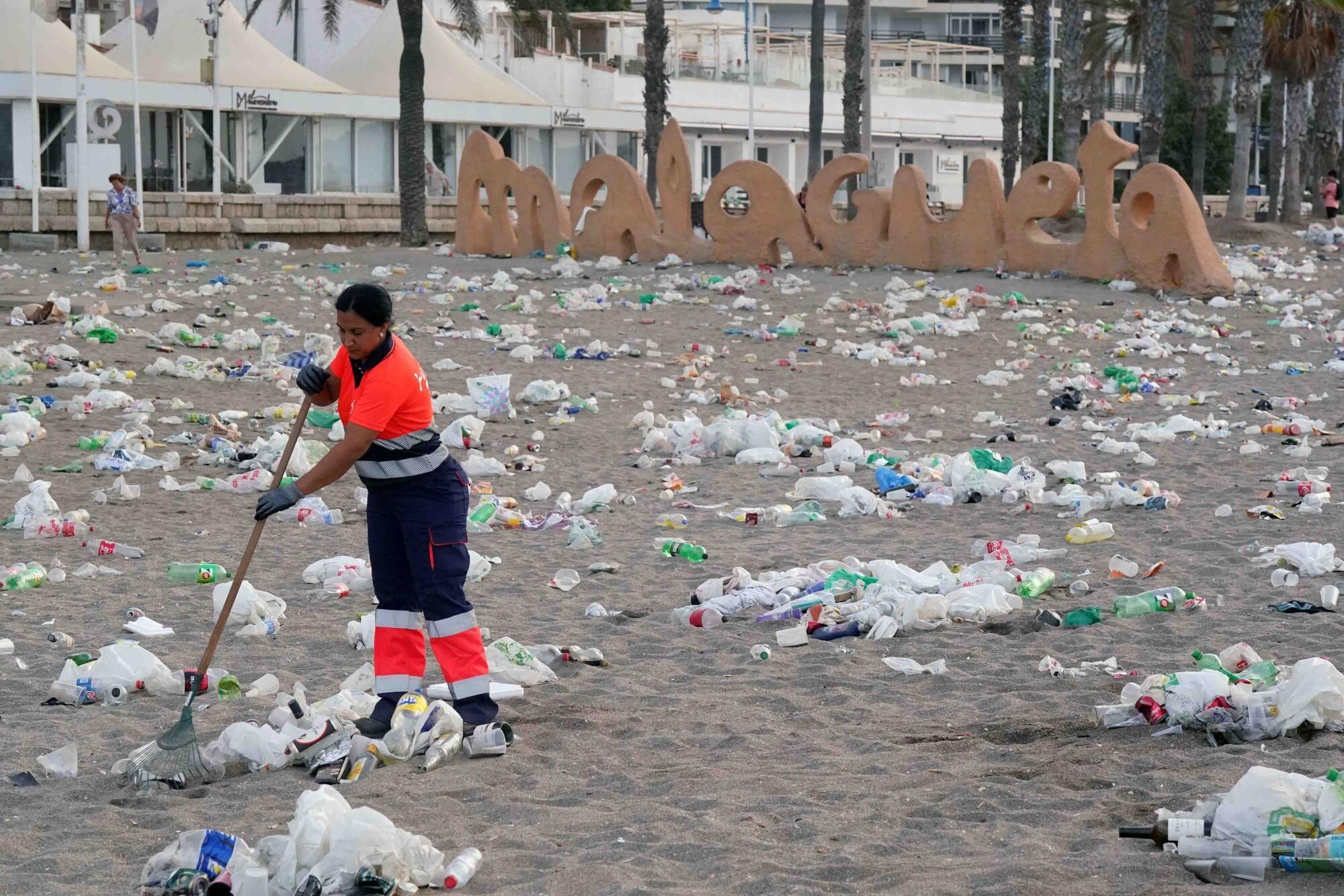 Varios operarios de la empresa de limpieza de Limasam, recogen los residuos de la playa de La Malagueta, tras la Noche de San Juan en Málaga 2025
