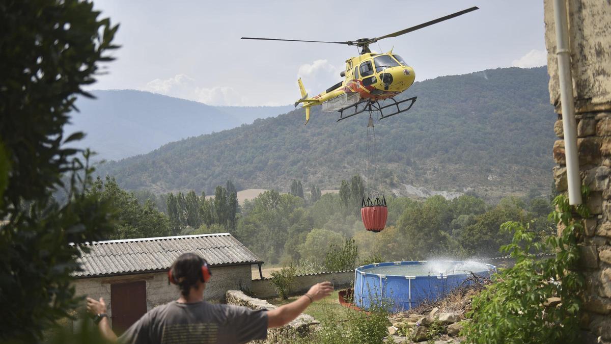 Un helicóptero recoge agua de una piscina de plástico en Atarés durante las labores de extinción de un incendio forestal
