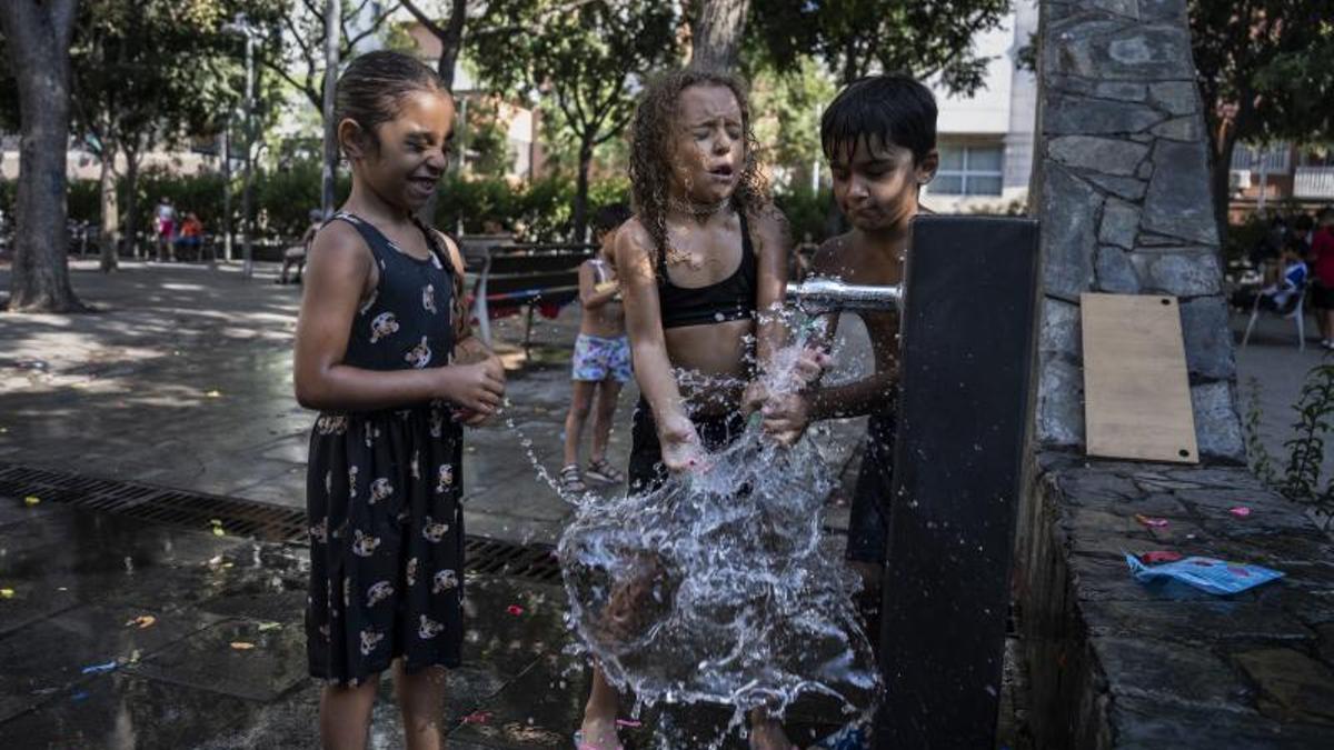 Niños de Santa Rosa, en Santa Coloma de Gramenet, juegan en una fuente para aliviar el calor.