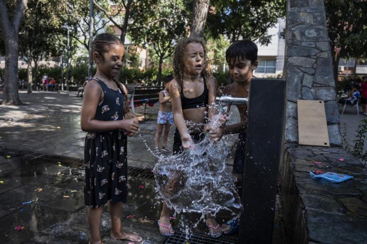 Niños de Santa Rosa, en Santa Coloma de Gramenet, juegan en una fuente para aliviar el calor.