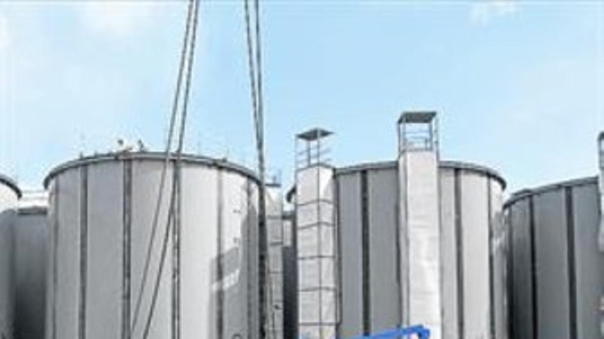 Dos operarios trabajan ante unos tanques de agua de Fukushima.