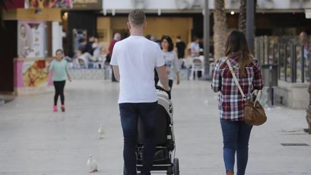 Una pareja joven con un niño en carricoche paseando por el centro de Elche, en una imagen reciente.